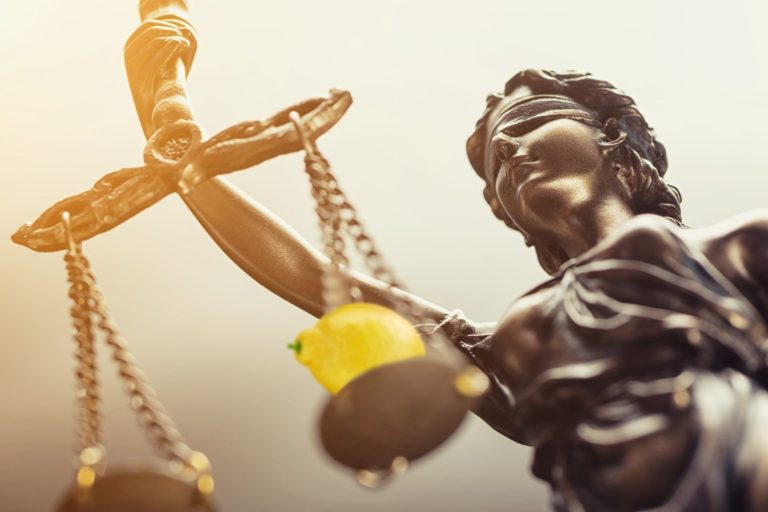Lady justice holding scales with a lemon on one side.